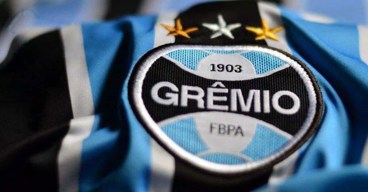 Foto mostra emblema do Grêmio em camisa do time.