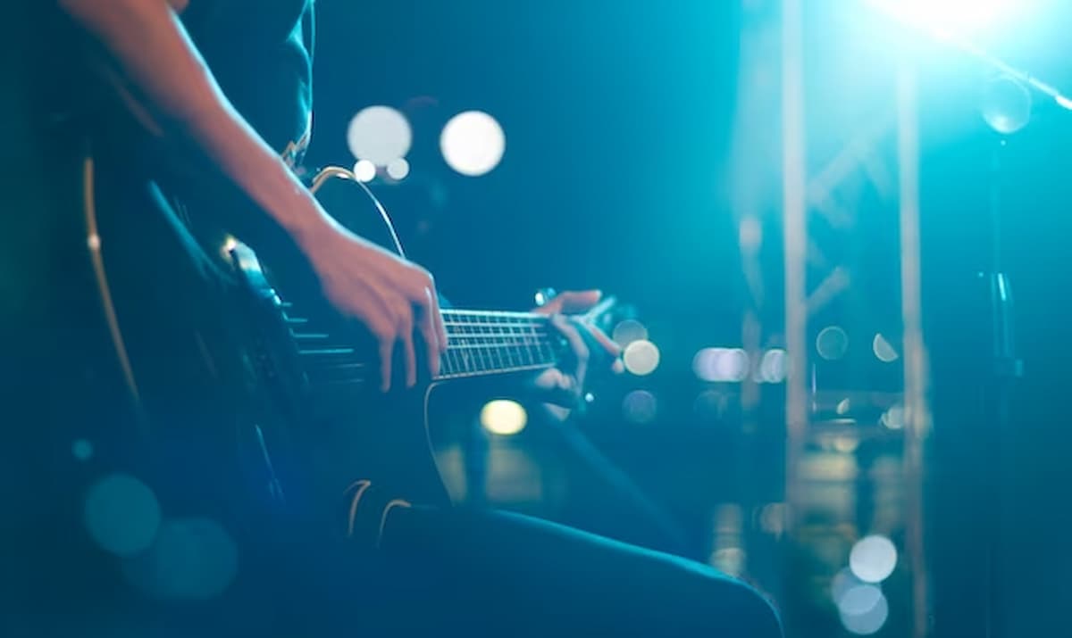 Imagem mostra pessoa tocando guitarra.
